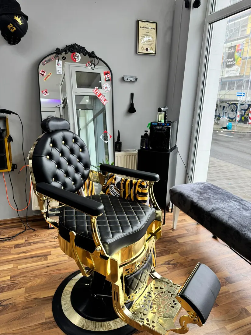 Goldener Barberstuhl mit schwarzem Chesterfield-Polster im Babo Barbershop Köln-Mülheim